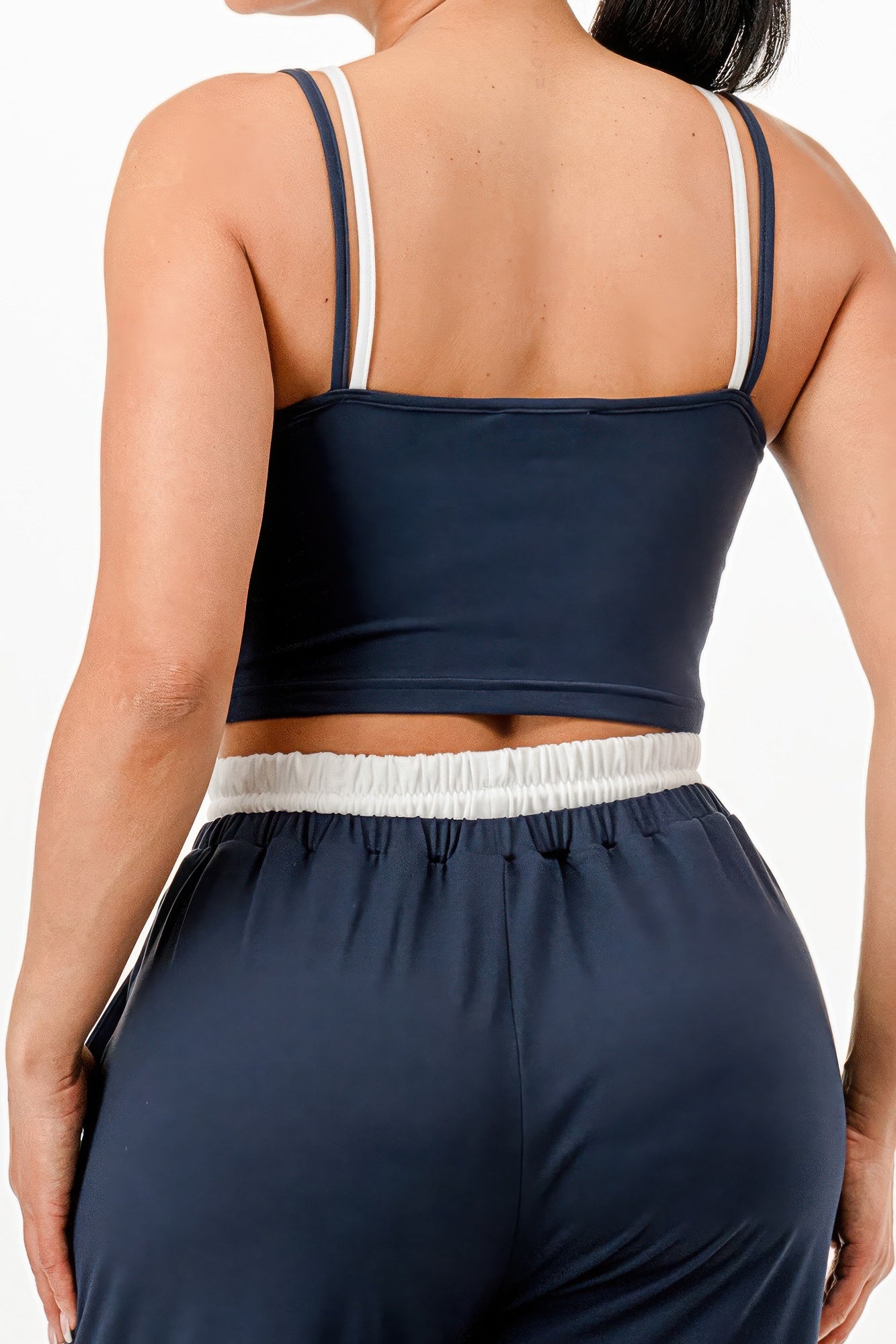 Back view of woman wearing a navy blue relaxed fit tank and jogger set with white strap accents