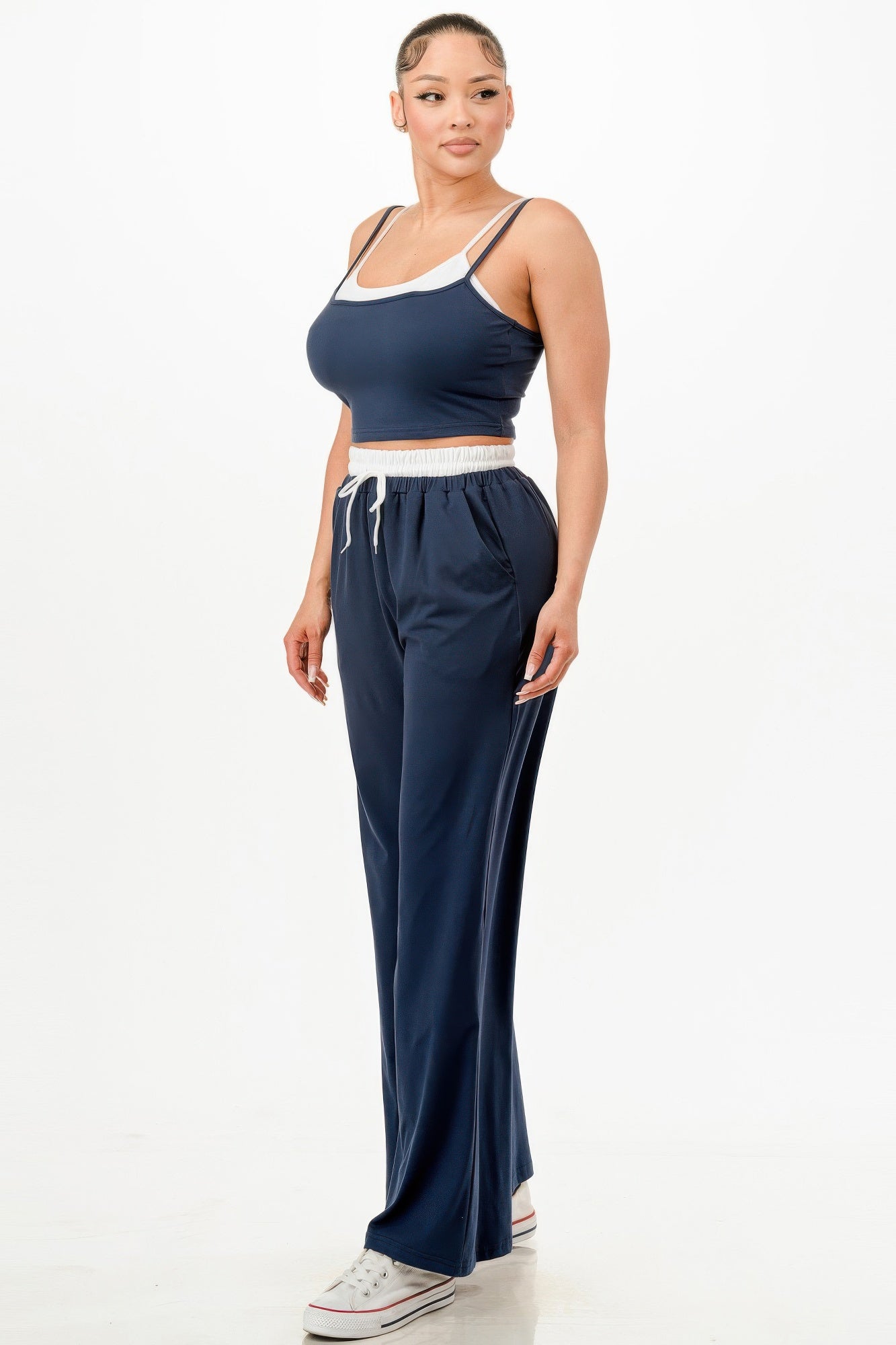 Woman wearing a navy blue relaxed fit tank and jogger set with white trim and white sneakers