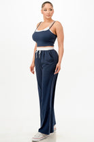 Woman wearing a navy blue relaxed fit tank and jogger set with white trim and white sneakers
