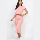 Woman wearing pink ribbed midi skirt set with short sleeves and white slip on shoes