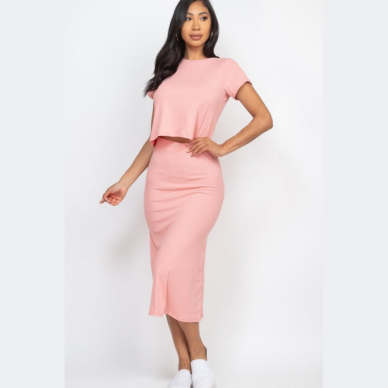 Woman wearing pink ribbed midi skirt set with short sleeves and white slip on shoes