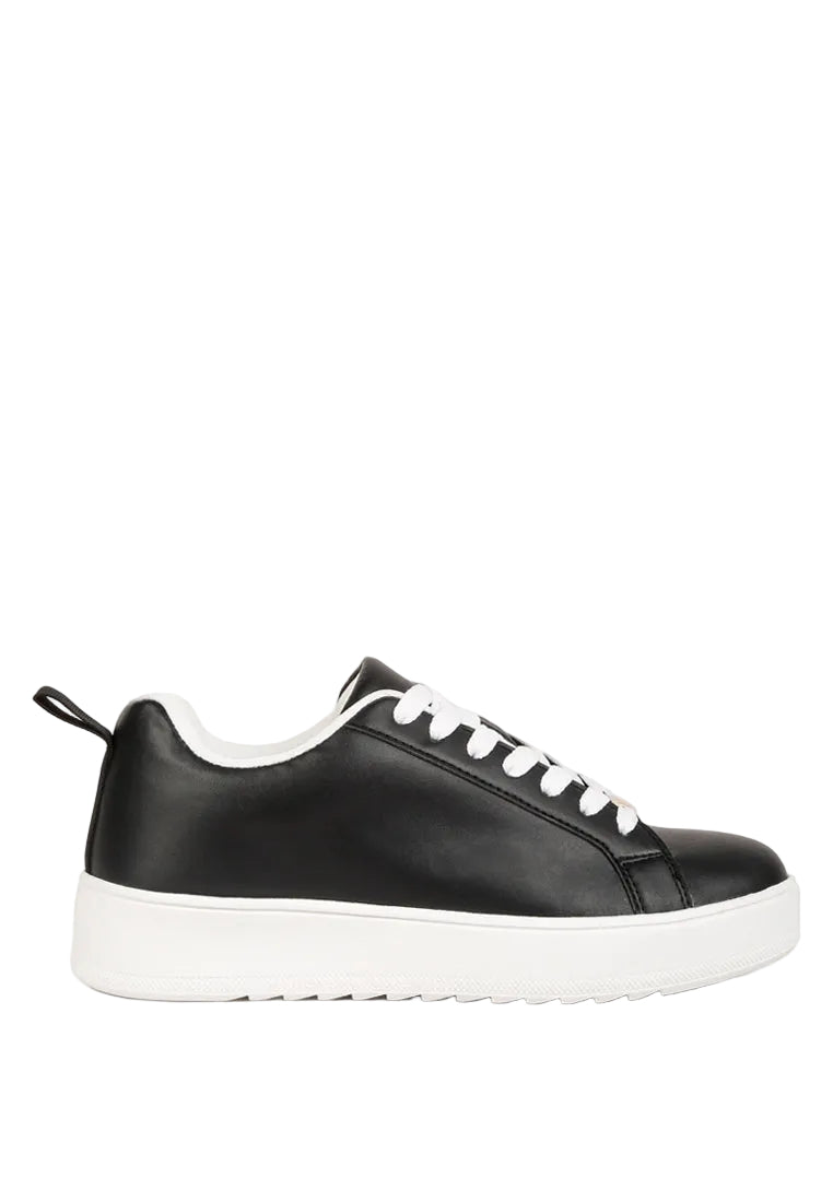 Black sneakers with white laces on a light gray background