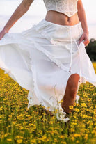 Flowy white ruffle drawstring waist skirt ideal for summer outings, paired with a stylish top in a flower field