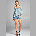 Women's ruffled front tie long sleeve blouse in soft blue paired with denim shorts