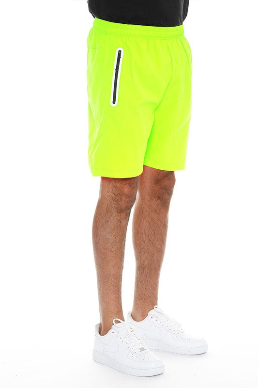 WEIV men's neon green running shorts with zip pocket and elastic waistband paired with white sneakers