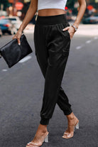 Women's black satin cargo joggers from VacationGrabs styled with clear heeled sandals and a white crop top