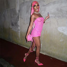 Woman wearing a bright pink see through mesh club dress with matching heels and accessories