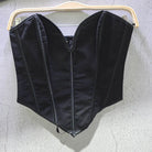 Black sexy party club bustier top hanging on wooden hanger against gray wall