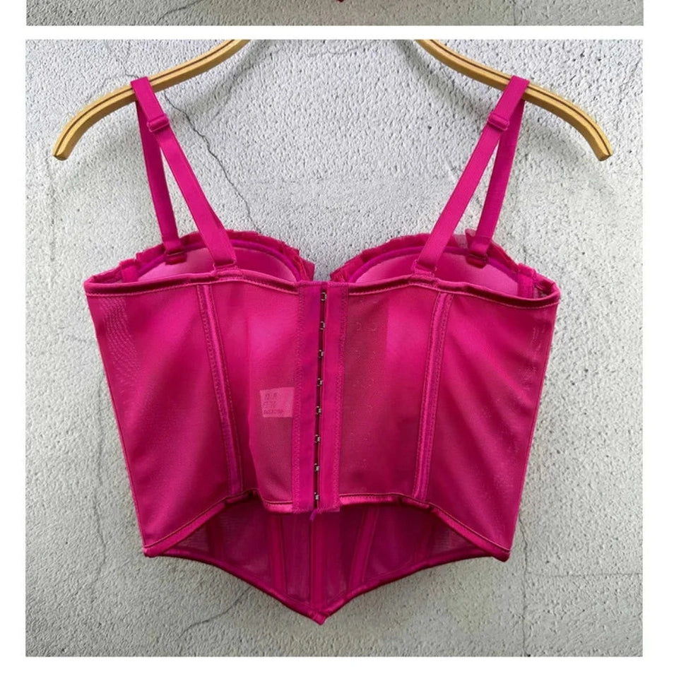 Pink sexy party club bustier top with adjustable straps hanging on a wooden hanger