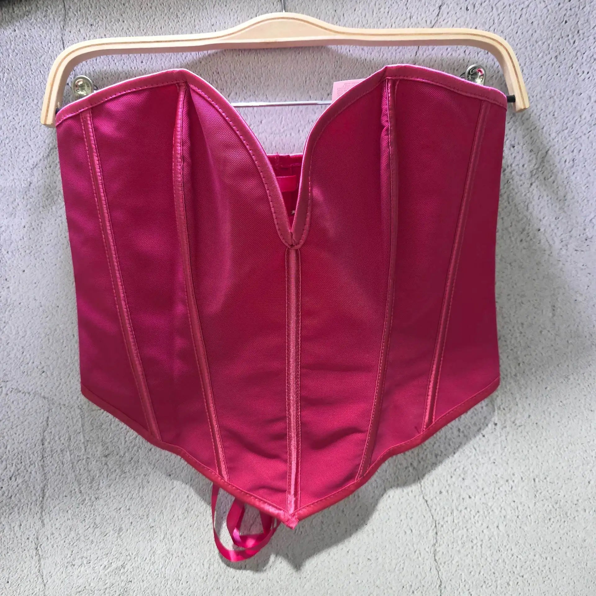 Bright pink sexy party club bustier top with structured seams hanging on wooden hanger