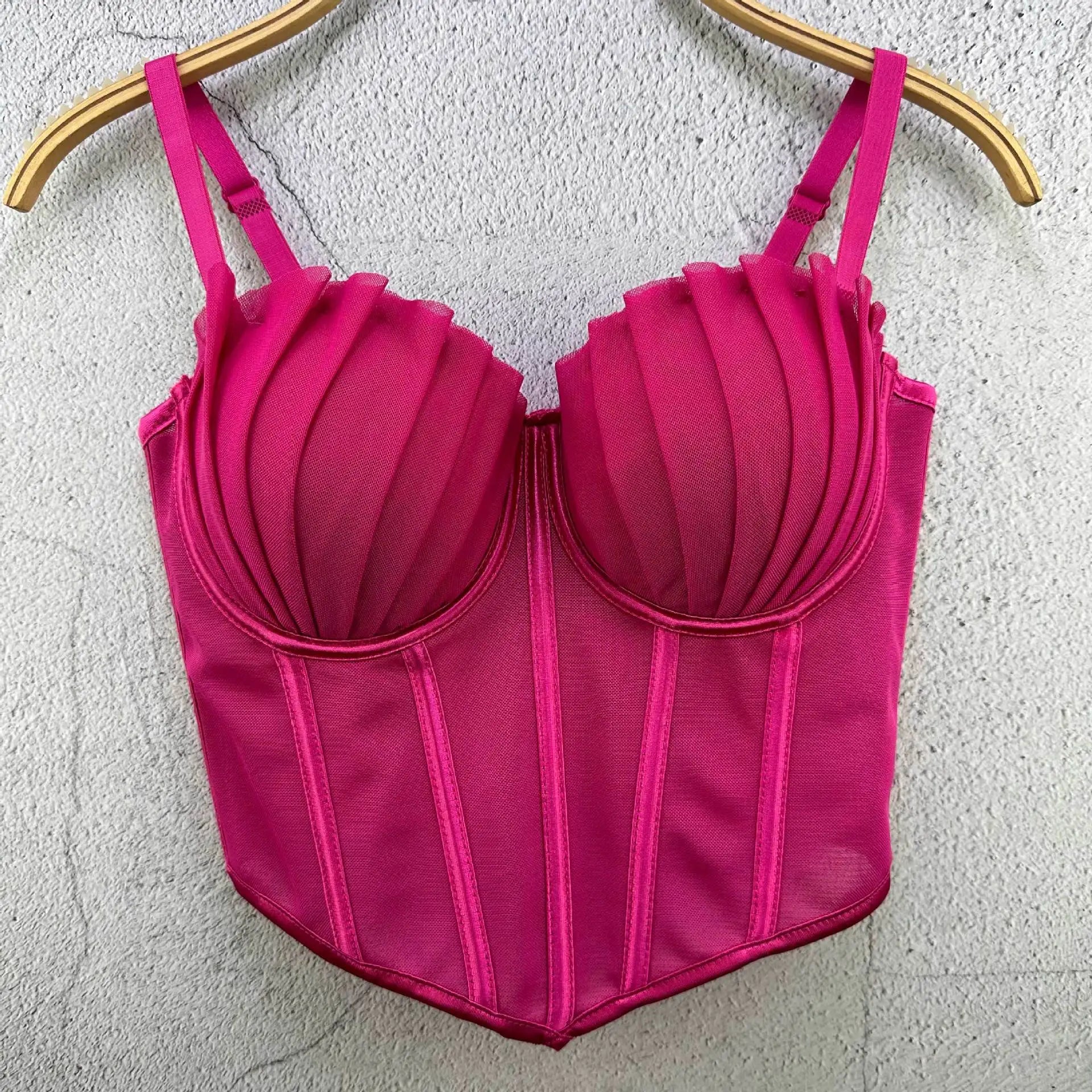 Pink sexy party club bustier top with structured cups and adjustable straps hanging on wooden hanger