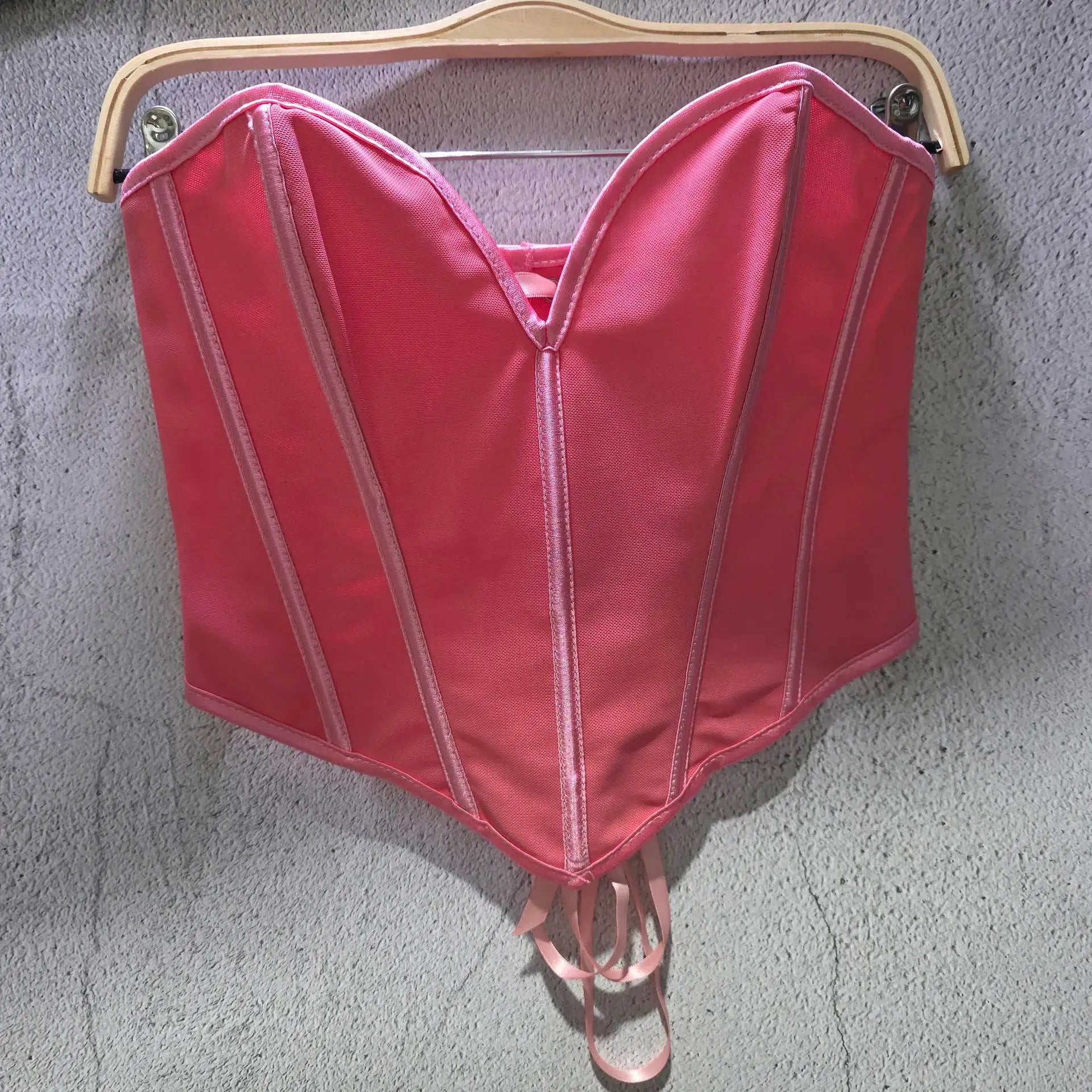 Pink sexy party club bustier top with structured seams hanging on wooden hanger