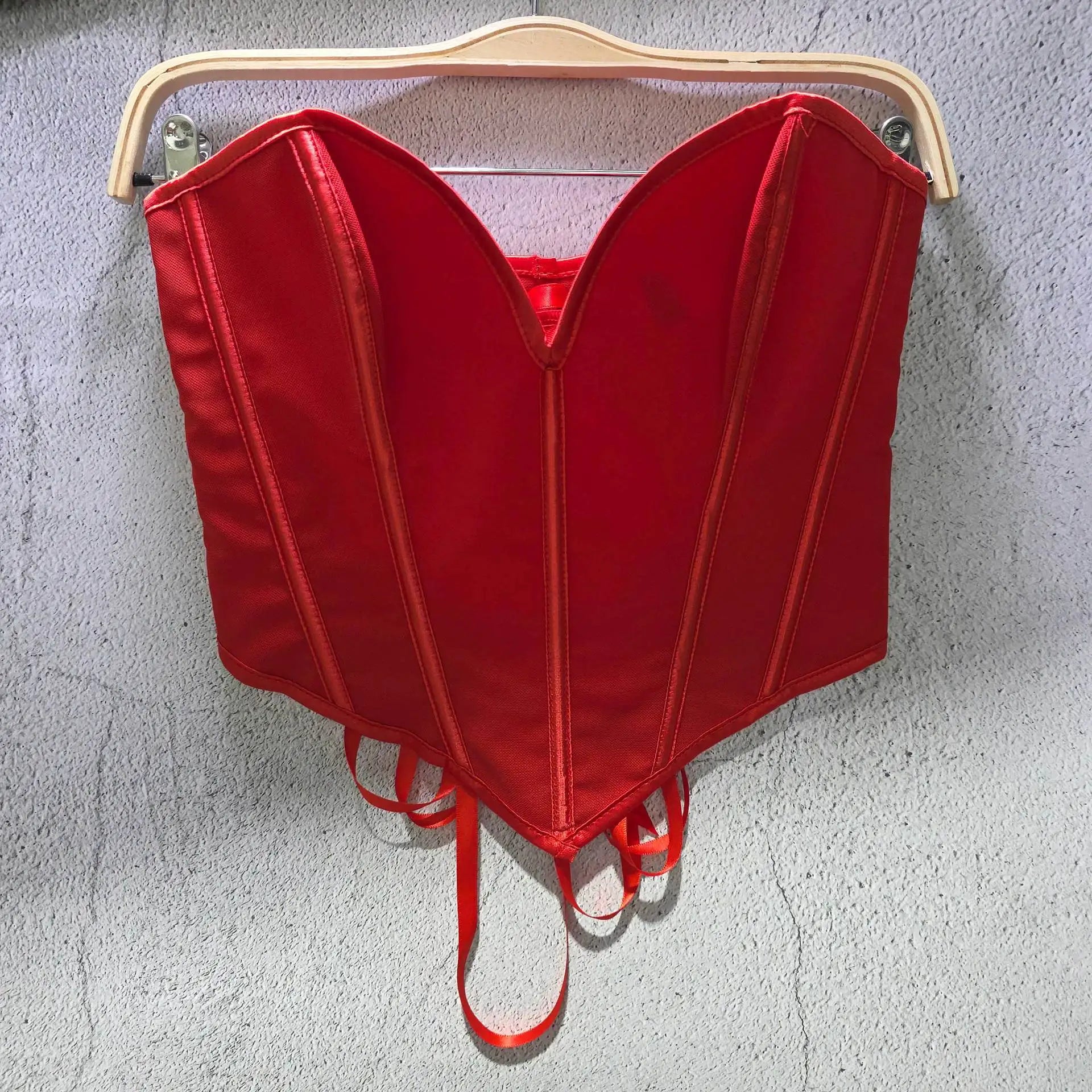 Red sexy party club bustier top with structured seams hanging on wooden hanger