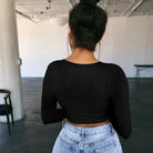 Back view of woman wearing a black sexy summer crop top for women paired with light blue jeans
