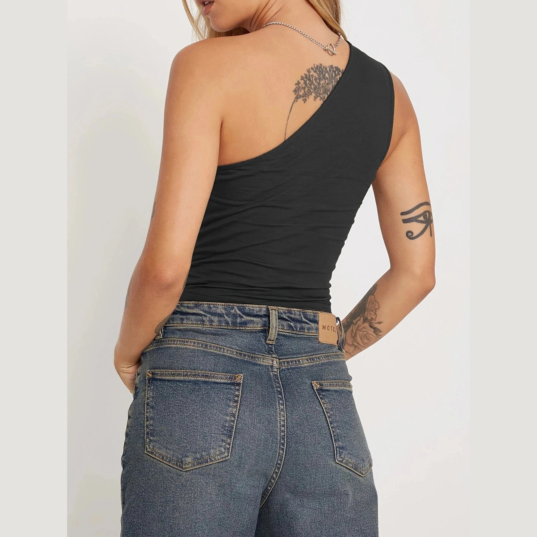 Black one-shoulder sexy vacation tops for women paired with high-waisted denim jeans