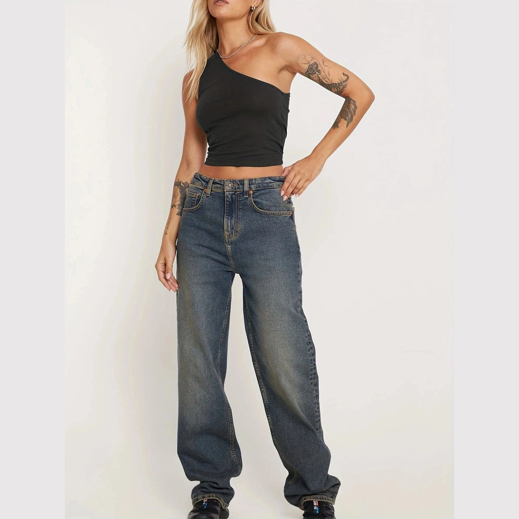 Woman wearing a black one-shoulder sexy vacation tops for women paired with relaxed fit jeans
