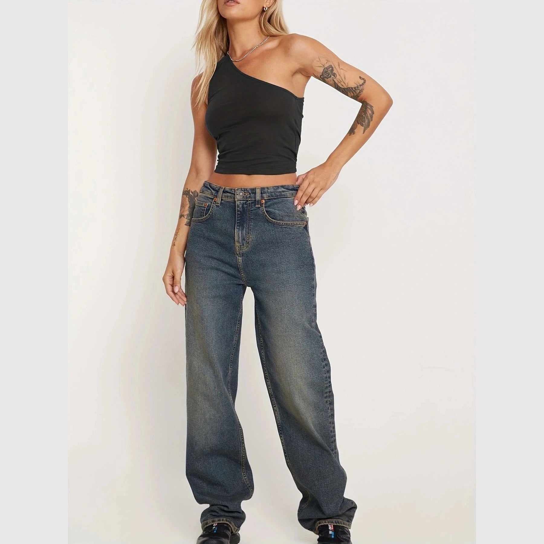 Woman wearing a black one-shoulder sexy vacation tops for women paired with relaxed fit jeans
