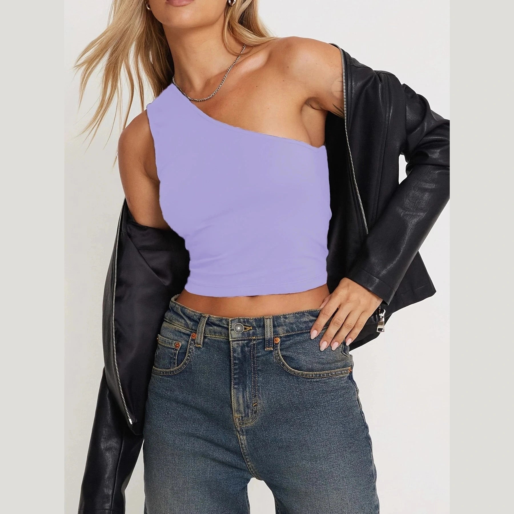 Woman wearing a stylish one-shoulder lavender crop top and black leather jacket showcasing sexy vacation tops for women