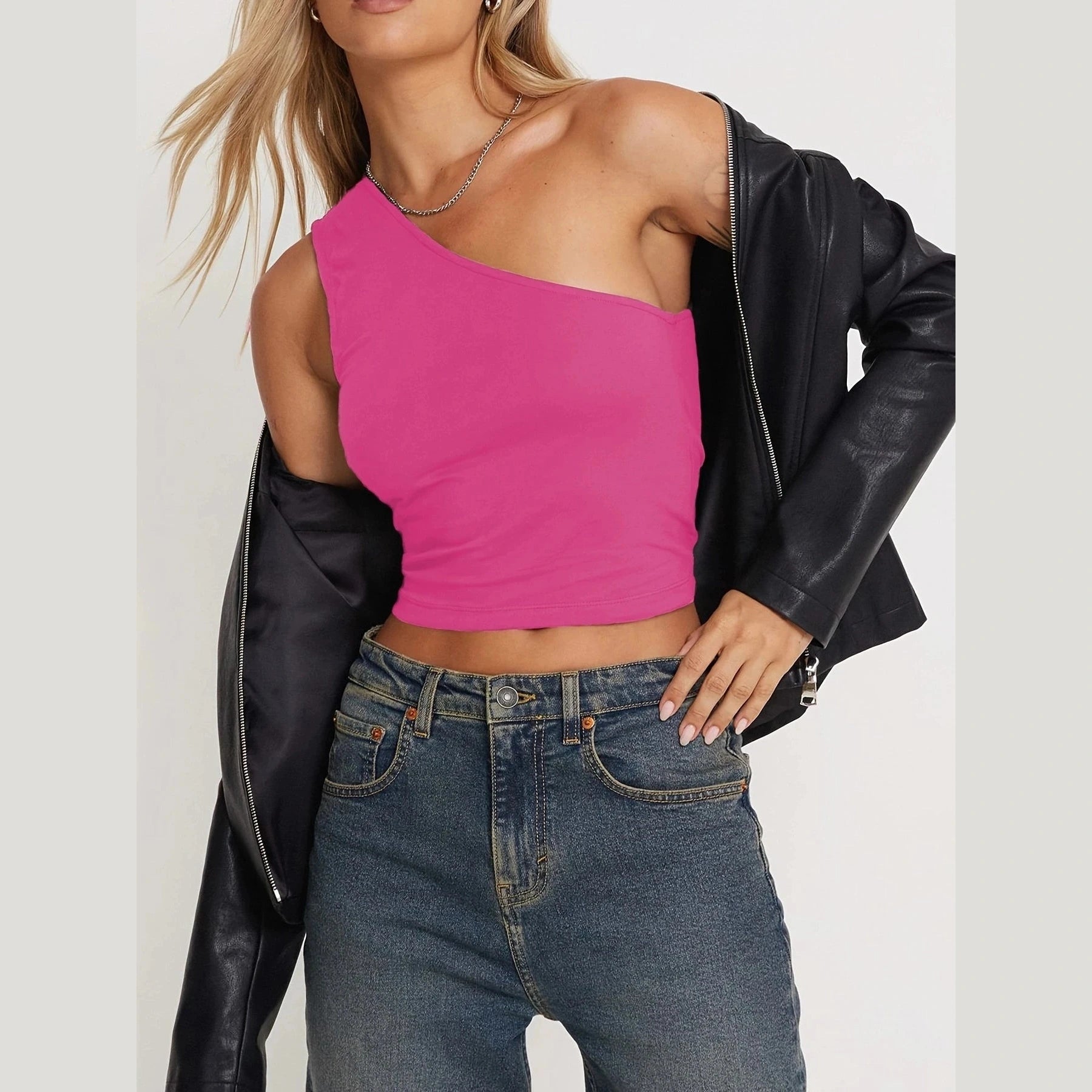 Woman wearing a pink one-shoulder sexy vacation tops for women paired with jeans and a black leather jacket