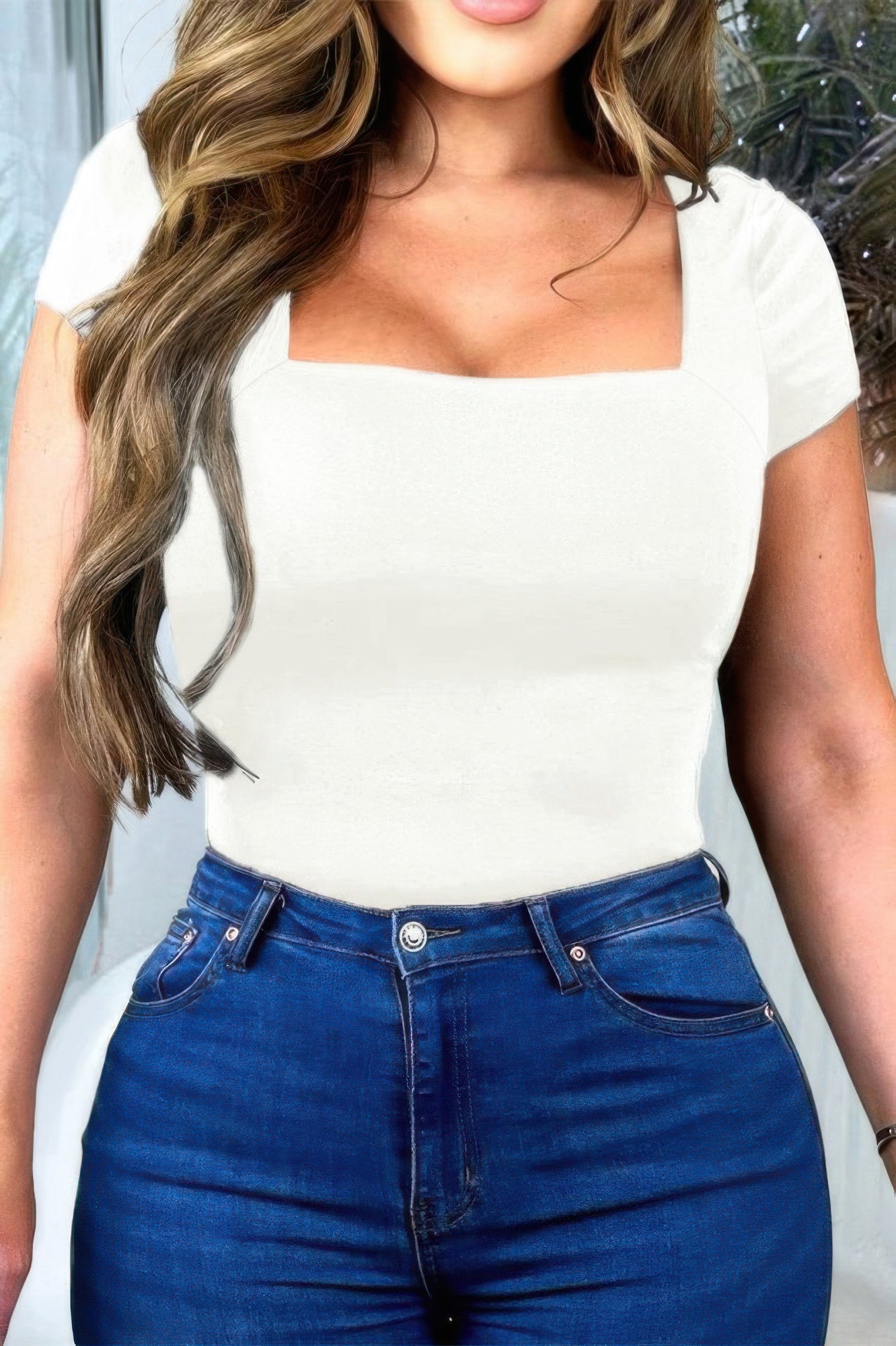 Women's short sleeve fitted summer top in white paired with blue high-waisted jeans