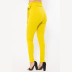 VacationGrabs women's yellow skinny pants with belt accent paired with black high heels