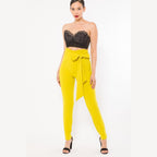 Women wearing yellow skinny pants with belt accent paired with black lace crop top and heels