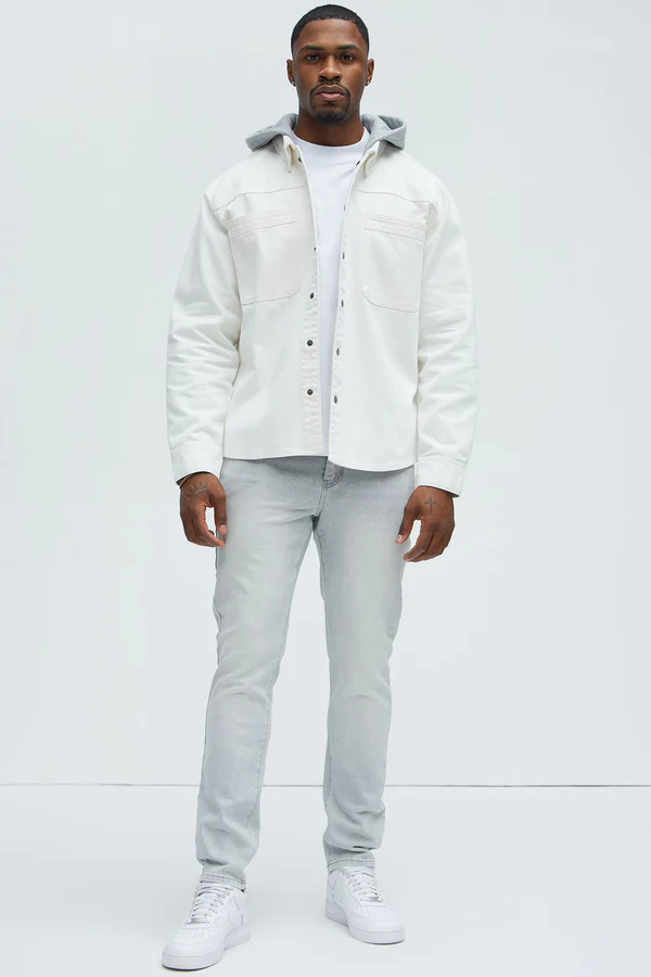 Man wearing slate grey jeans for men paired with white jacket and sneakers