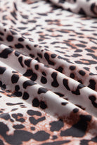 Close-up of JUNIPER BLVD smocked neck long sleeve bodysuit fabric with a stylish leopard print design