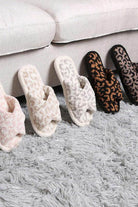 Soft crossover slippers for women in various colors and animal prints displayed on a plush rug
