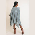 Woman wearing a soft open front kimono in green tones, styled with brown cowboy boots