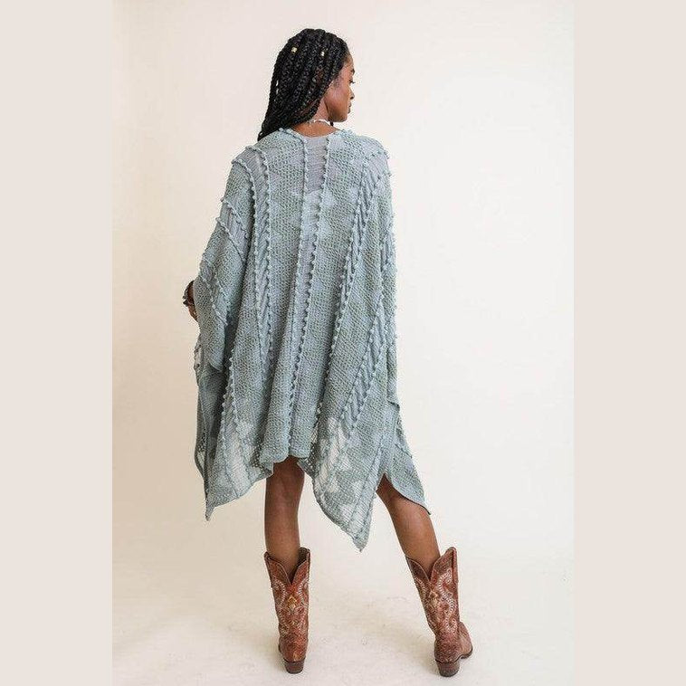 Woman wearing a soft open front kimono in green tones, styled with brown cowboy boots