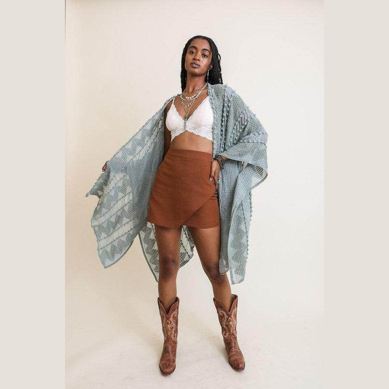 Stylish model wearing a soft open front kimono over a crop top with a brown skirt and western boots