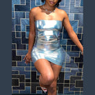 Woman wearing a strapless silver bodycon mini dress standing against a geometric patterned wall