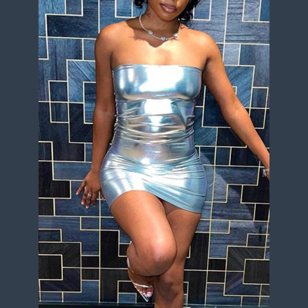 Woman wearing a strapless silver bodycon mini dress standing against a geometric patterned wall