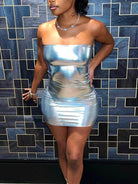 Woman wearing a strapless silver bodycon mini dress standing against a geometric tiled wall