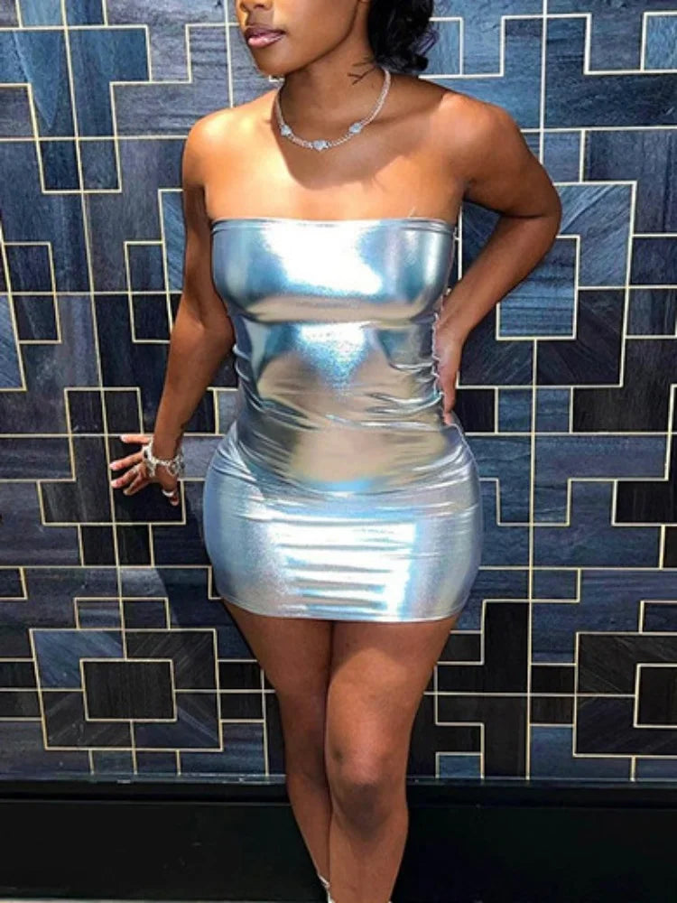 Woman wearing a strapless silver bodycon mini dress standing against a geometric tiled wall