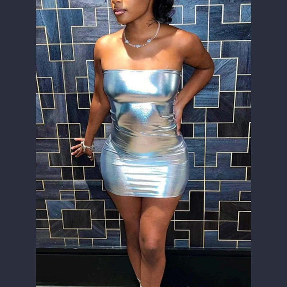 Woman wearing a strapless silver bodycon mini dress standing against a geometric tiled wall