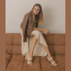 Stylish women's strappy alligator heel shoes paired with a chic outfit on a sofa