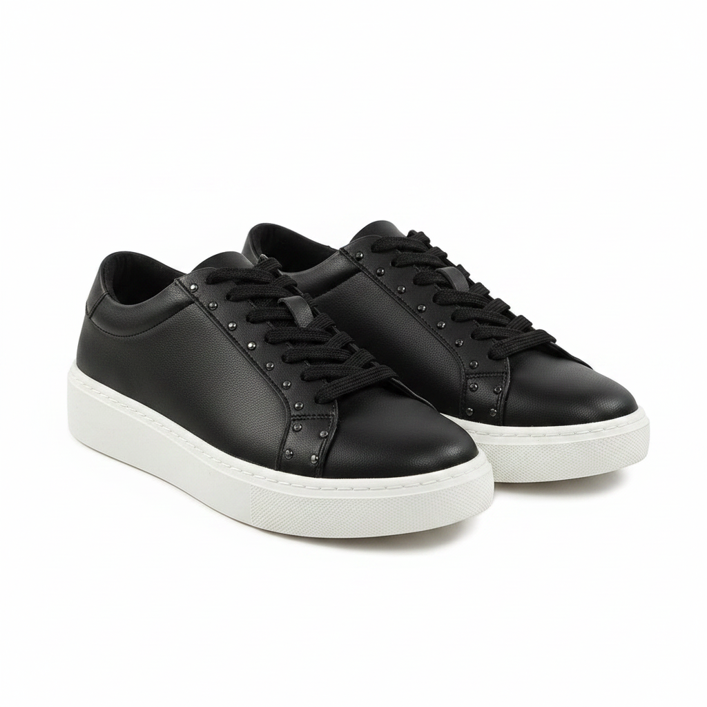 Black sneakers worn with light blue jeans on a white background
