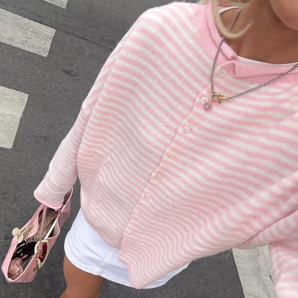 Close-up of a pink and white striped knit cardigan with button-front closure, worn with a gold necklace