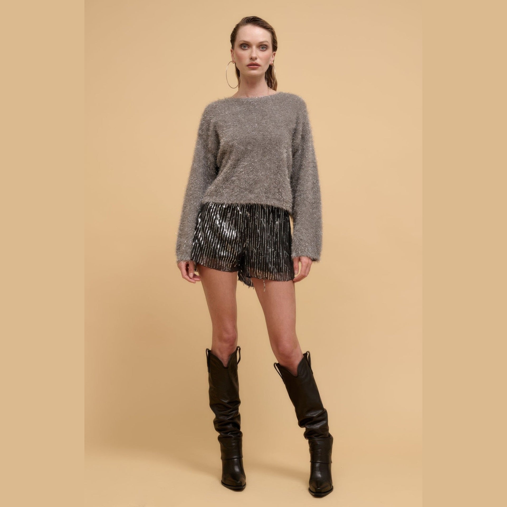Women wearing striped sequin high waist shorts paired with a fuzzy gray sweater and black boots