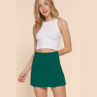 VacationGrabs stylish high waist mini skort in green worn with white sleeveless crop top