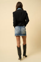 Back view of a stylish mini skirt for women paired with a black blazer and tall boots