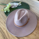 Stylish panama hat in light pink with a brown band on a wooden surface