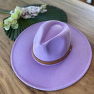 Stylish panama hat in lavender color with a brown leather band placed on a wooden surface