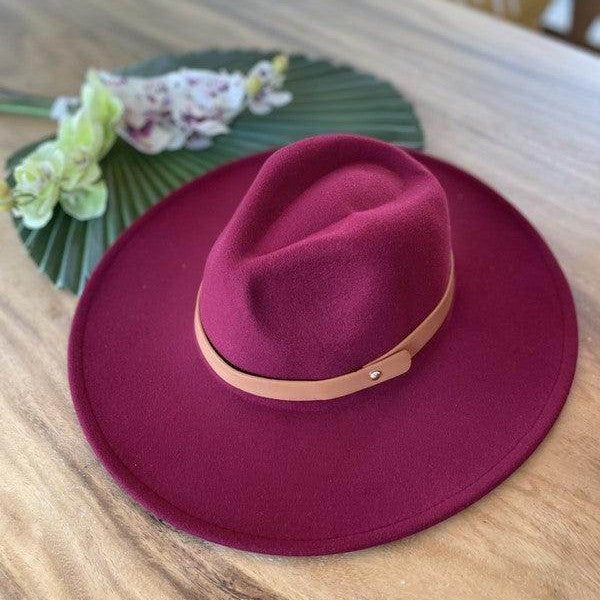 Queens INC stylish panama hat in burgundy with a leather band on a wooden table
