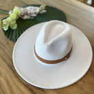 Queens INC stylish panama hat in white with a brown band on a wooden table