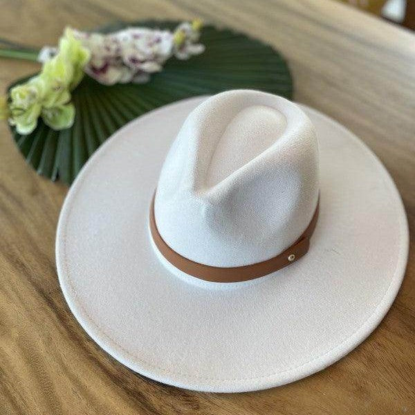 Queens INC stylish panama hat in white with a brown band on a wooden table