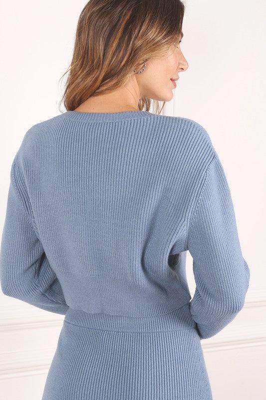 Back view of a woman wearing a stylish ribbed knit ensemble in soft blue color.