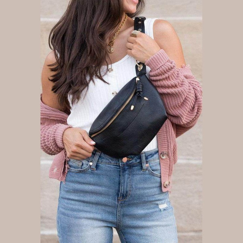Woman holding a stylish travel waist pack in black, perfect for hands-free convenience while traveling